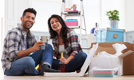 Couple sitting on floor surrounded by packing boxes